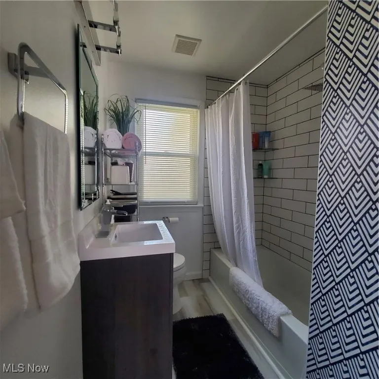 Full bath featuring vanity and shower / bath combo with shower curtain