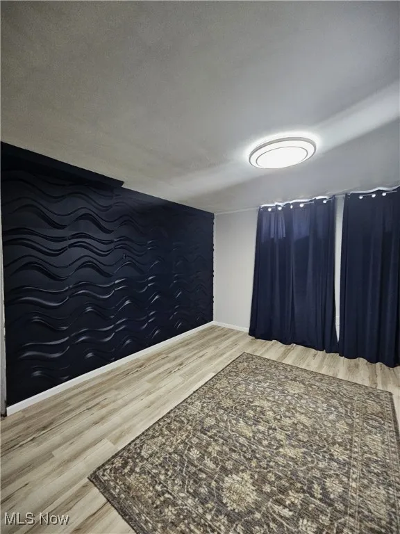 Unfurnished room with wood finished floors, an accent wall, and a textured ceiling