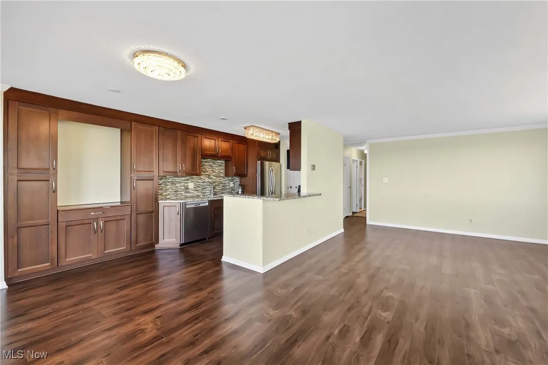 Kitchen with baseboards, dark wood finished floors, open floor plan, decorative backsplash, and appliances with stainless steel finishes