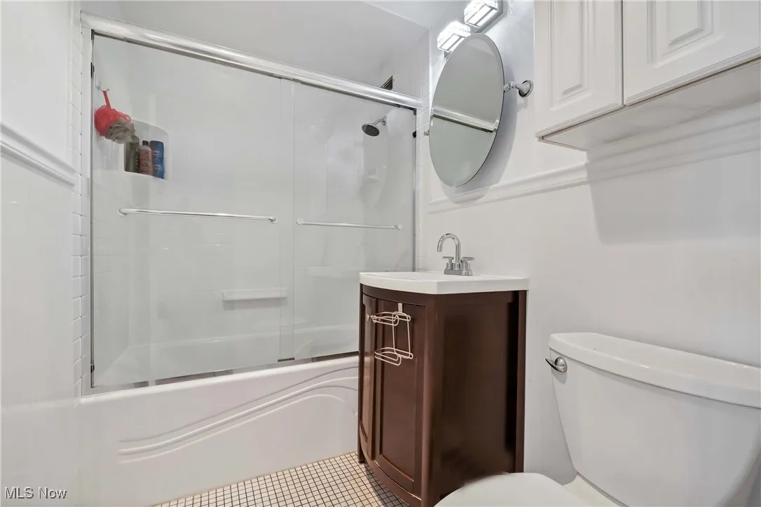 Bathroom with vanity, toilet, tile patterned flooring, and shower / bath combination with glass door