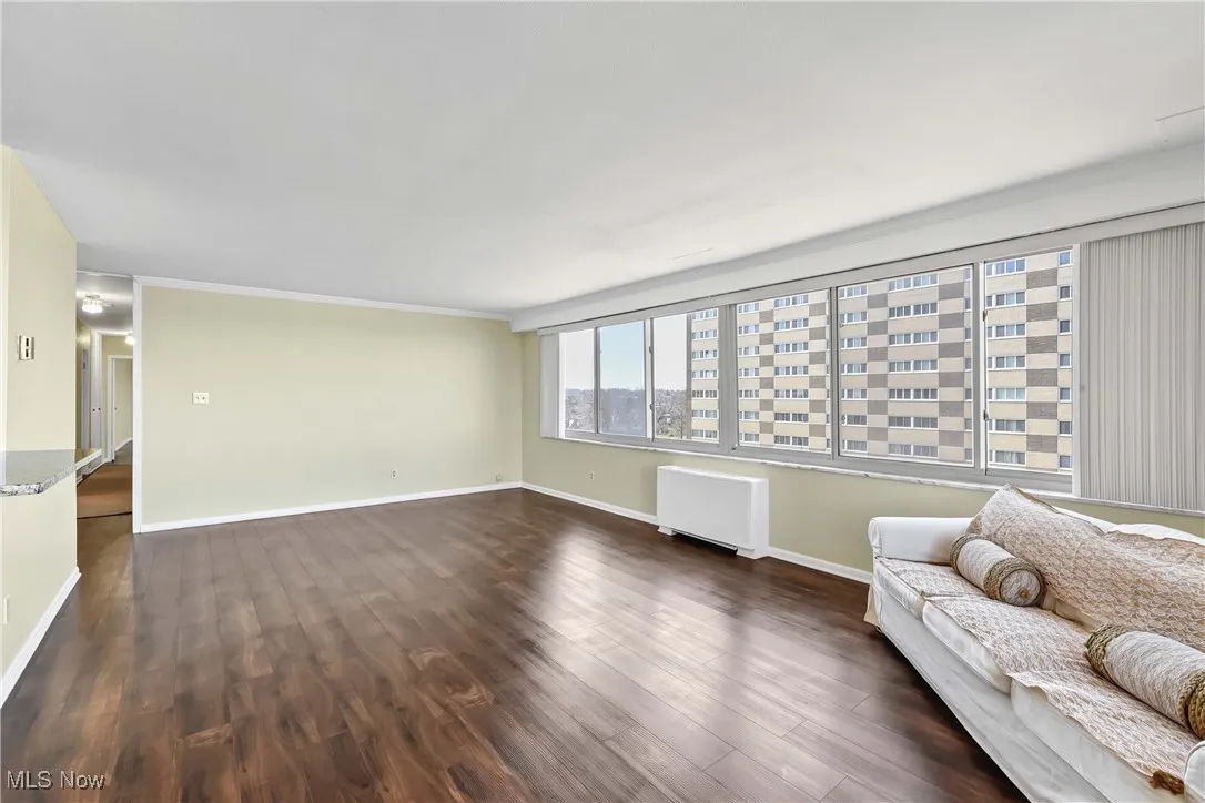Unfurnished living room with dark wood finished floors, radiator, and baseboards