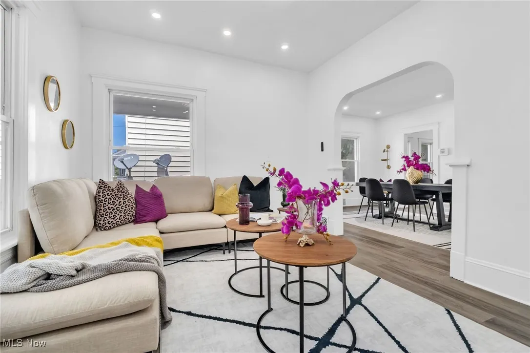 Living room with arched walkways, wood finished floors, healthy amount of natural light, and recessed lighting