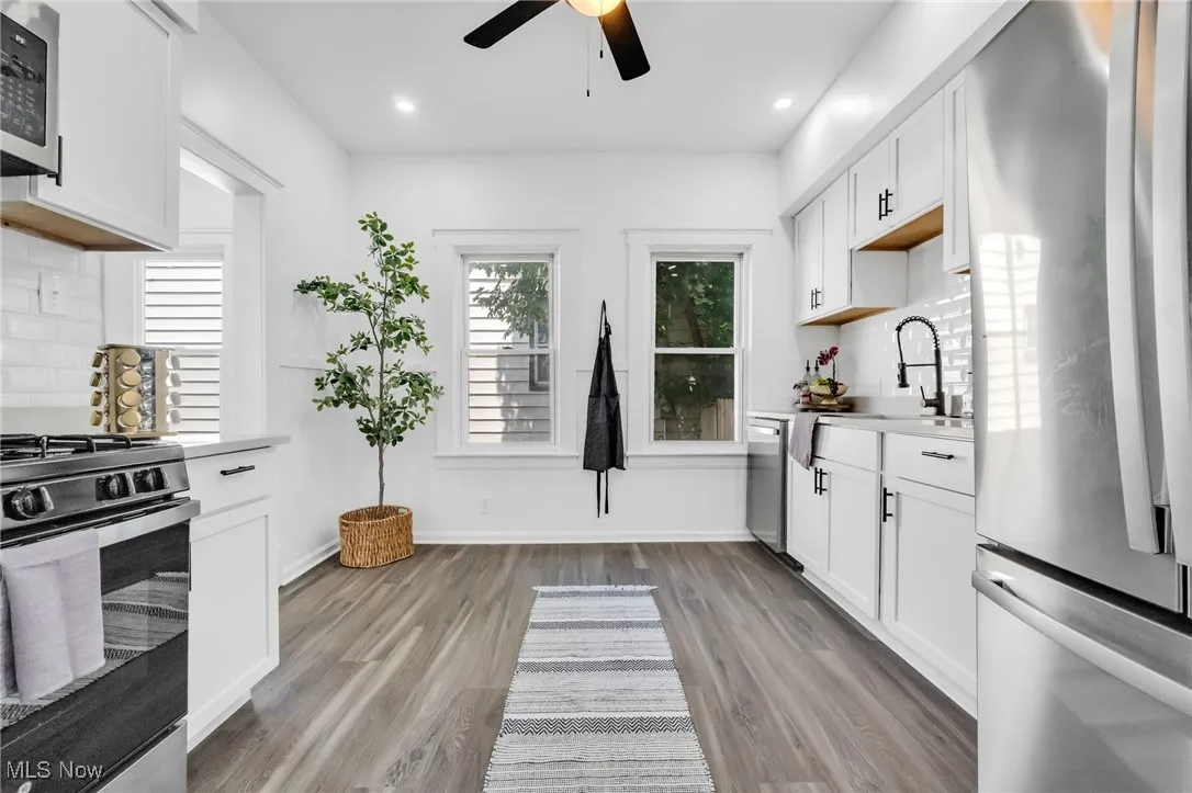 Kitchen featuring appliances with stainless steel finishes, a ceiling fan, light wood finished floors, light countertops, and white cabinetry