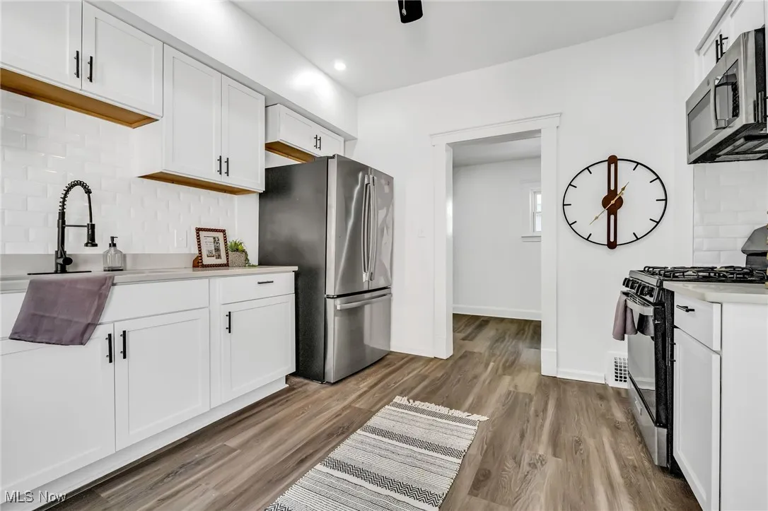 Kitchen featuring appliances with stainless steel finishes, backsplash, light countertops, wood finished floors, and recessed lighting