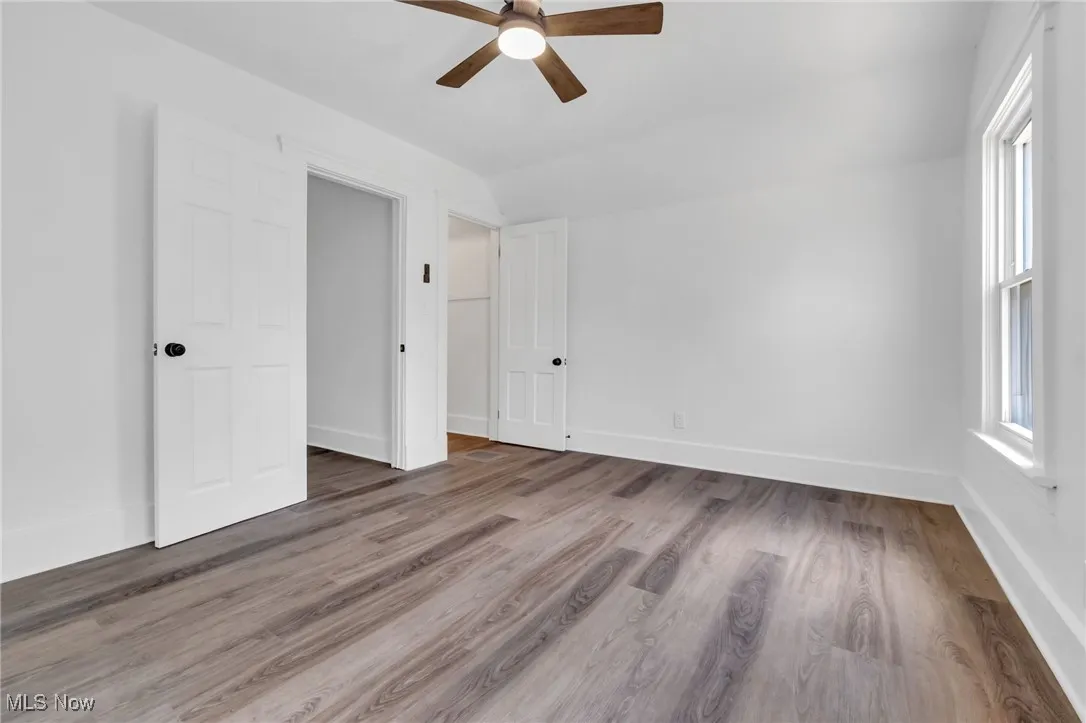 Unfurnished bedroom featuring lofted ceiling, wood finished floors, and ceiling fan
