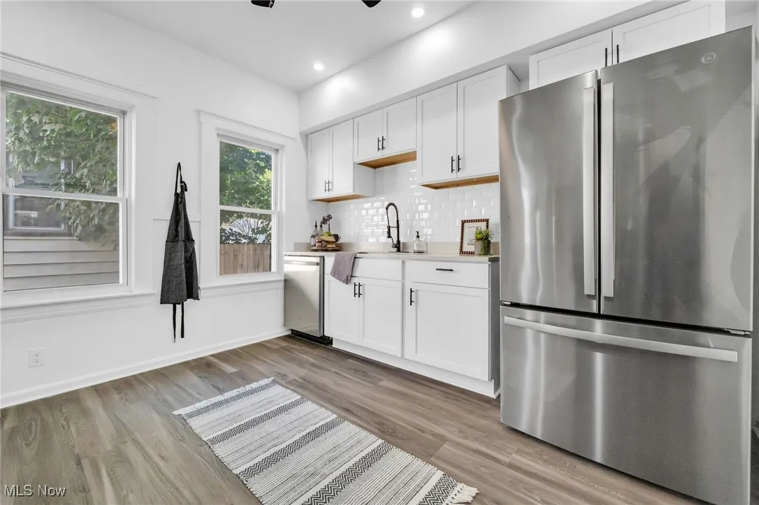 Kitchen with appliances with stainless steel finishes, light wood-style floors, white cabinets, backsplash, and recessed lighting