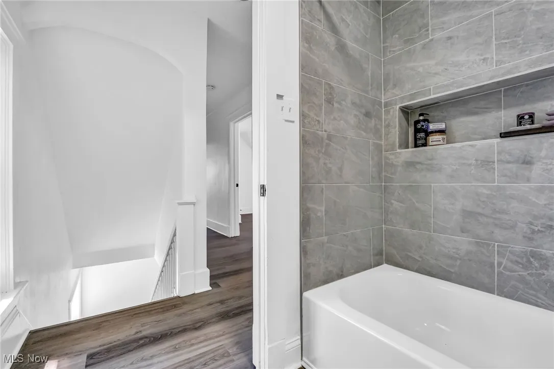 Full bath with a bath and wood finished floors