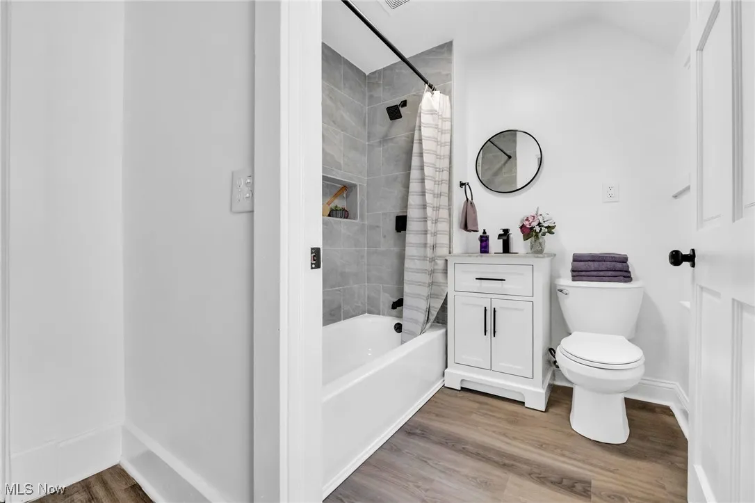 Bathroom featuring shower / bathtub combination with curtain, vanity, and wood finished floors