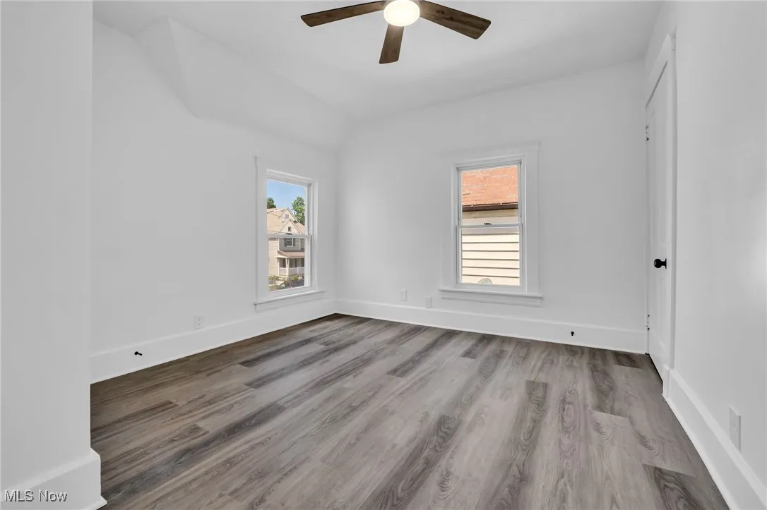 Empty room with a ceiling fan, wood finished floors, and lofted ceiling