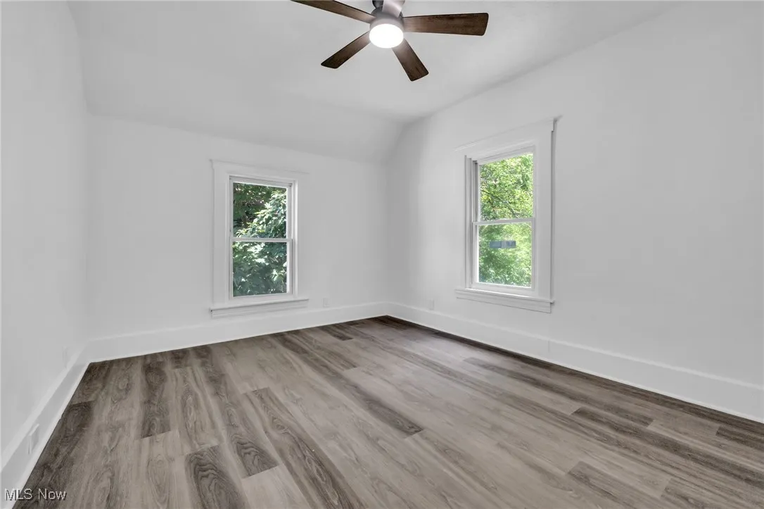 Unfurnished room with healthy amount of natural light, lofted ceiling, ceiling fan, and wood finished floors