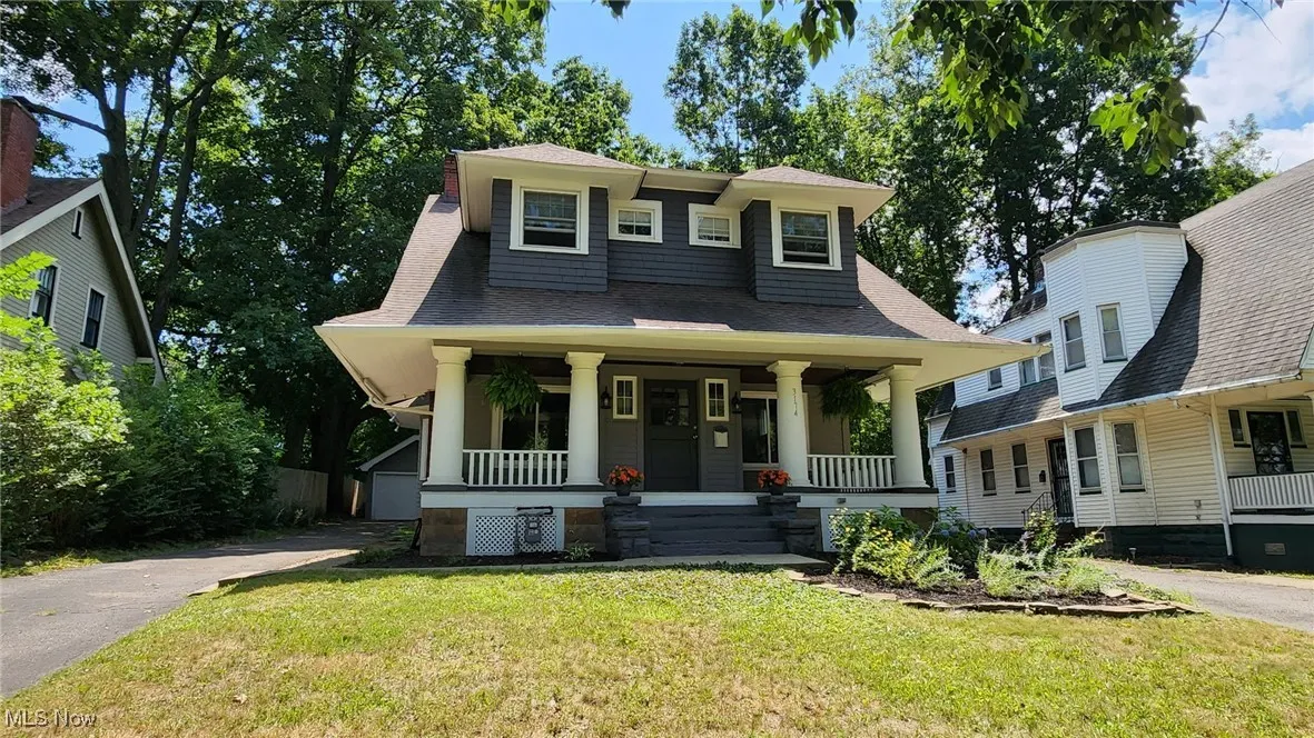 View of front of property with covered porch, roof with shingles, and a front lawn