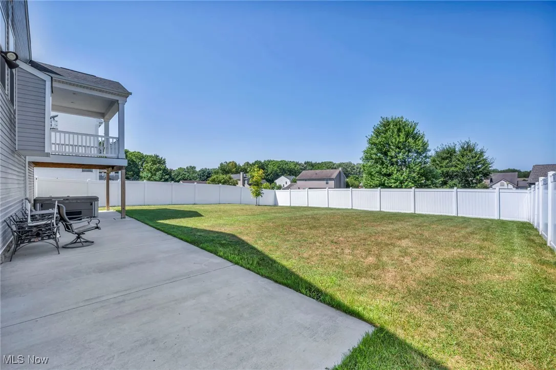 Fenced backyard with a patio area and a balcony