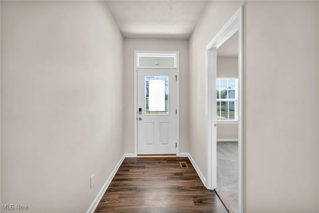 Entryway with dark wood finished floors and baseboards