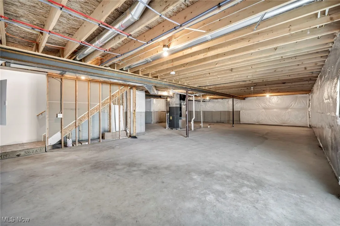 Unfinished below grade area with electric panel and heating unit