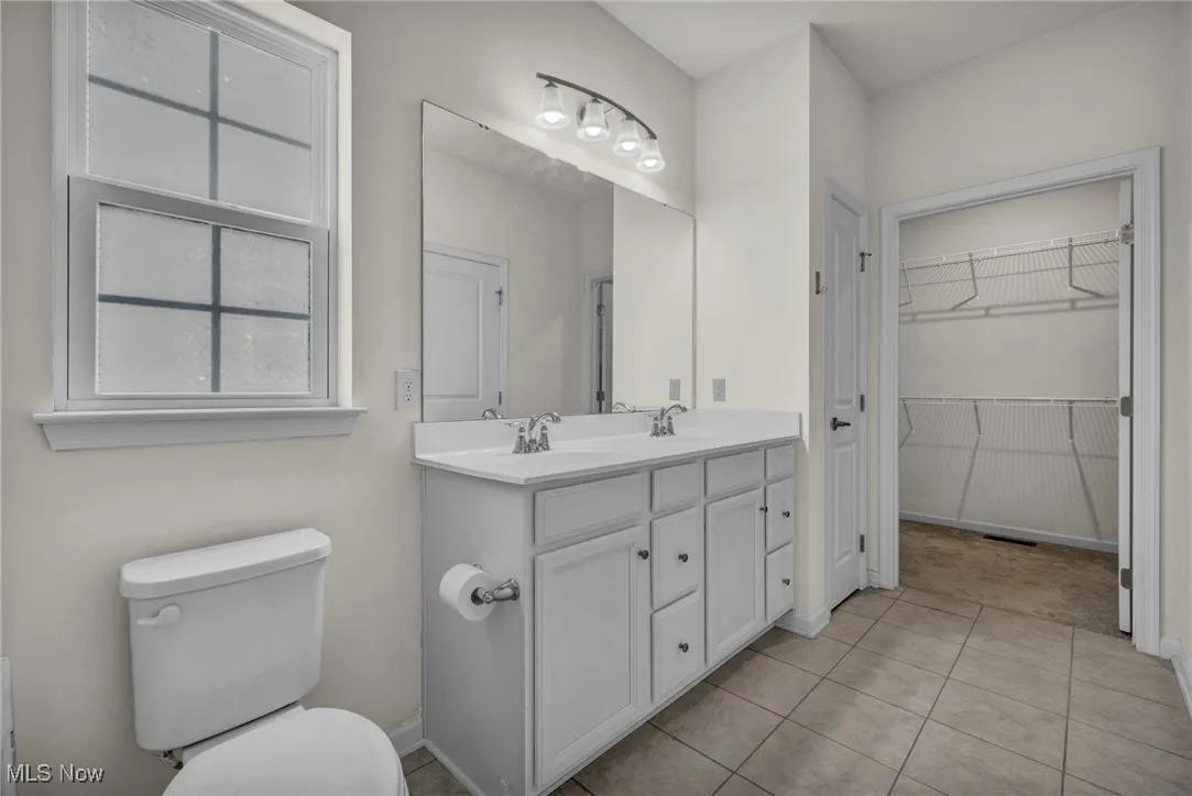 Bathroom with double vanity, tile patterned flooring, and a walk in closet