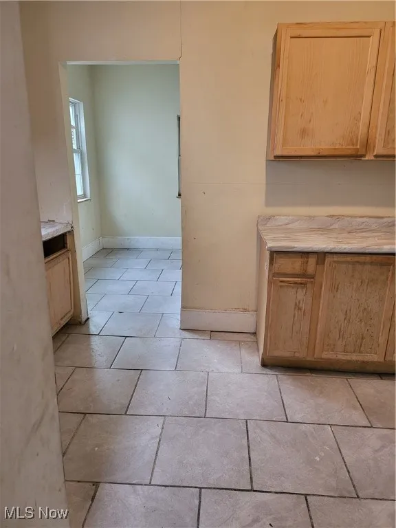 Unfurnished dining area featuring light tile patterned flooring and baseboards