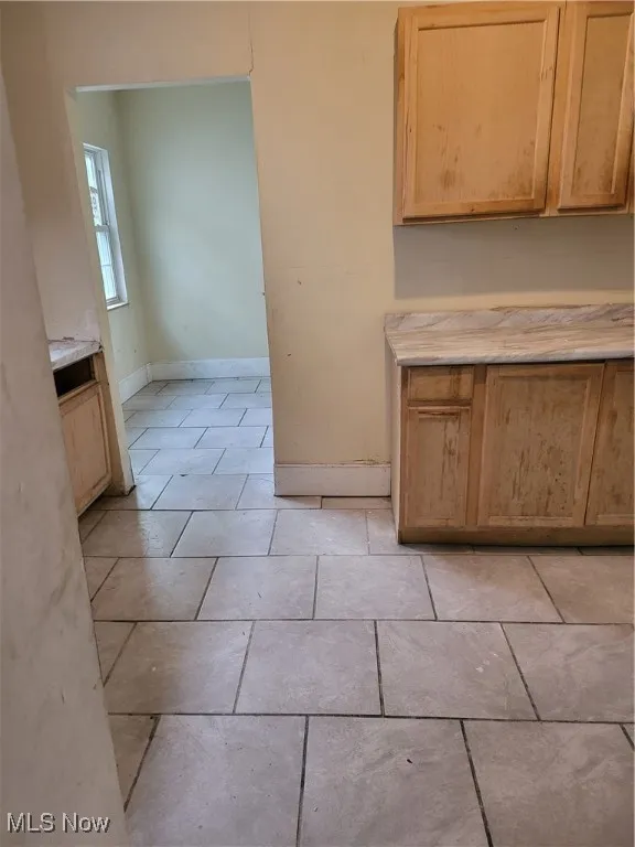 Kitchen with light countertops, light brown cabinetry, and light tile patterned floors