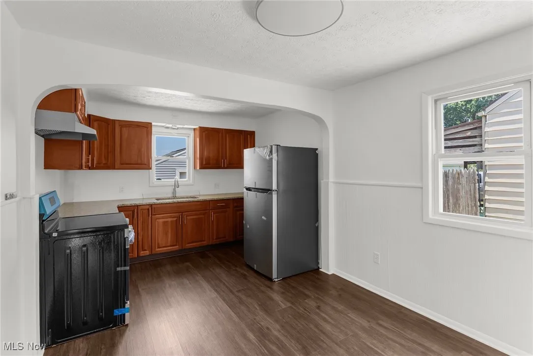 Kitchen featuring wainscoting, freestanding refrigerator, range, dark wood finished floors, and under cabinet range hood