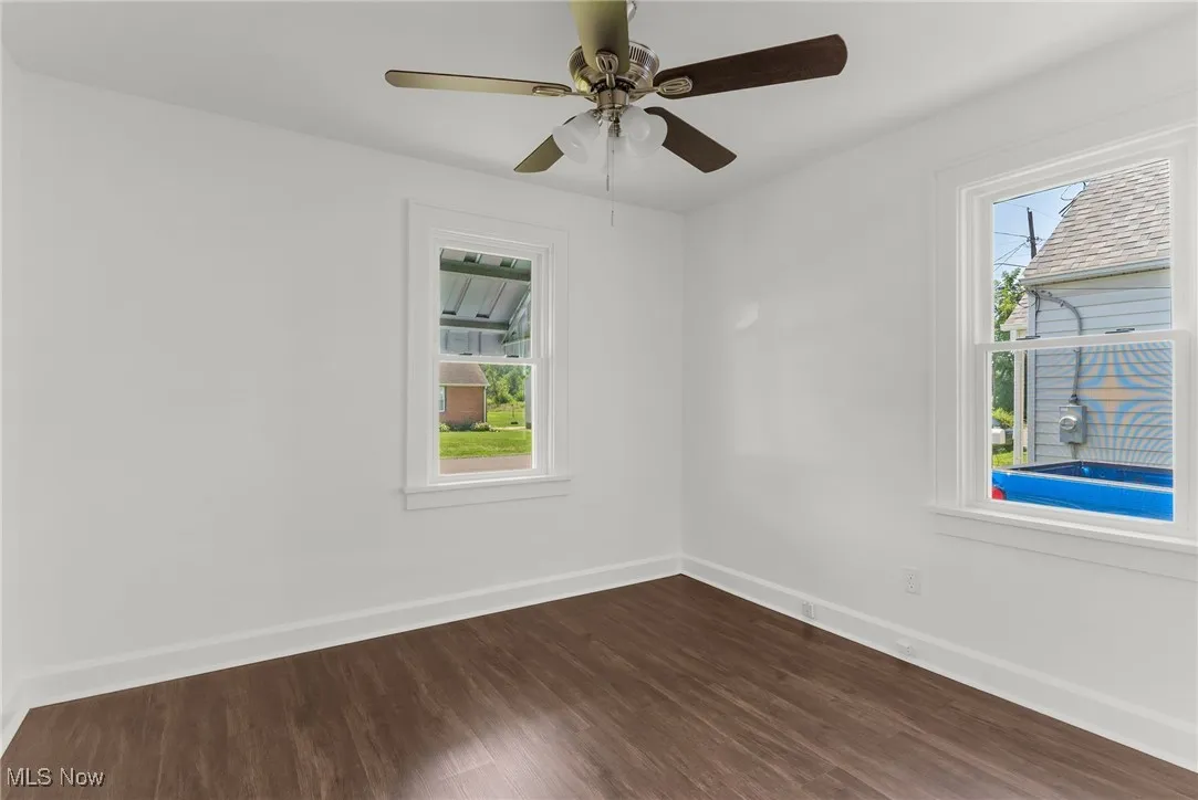 Unfurnished room with dark wood-type flooring and ceiling fan