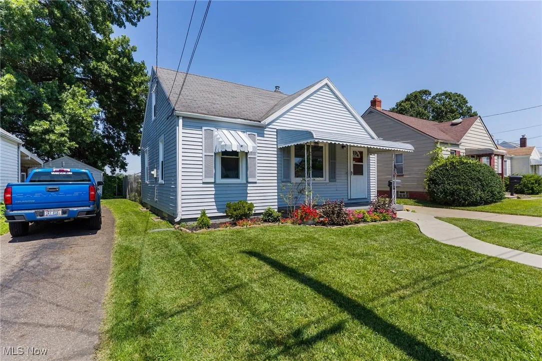 Bungalow-style house with a front lawn, a shingled roof, and driveway