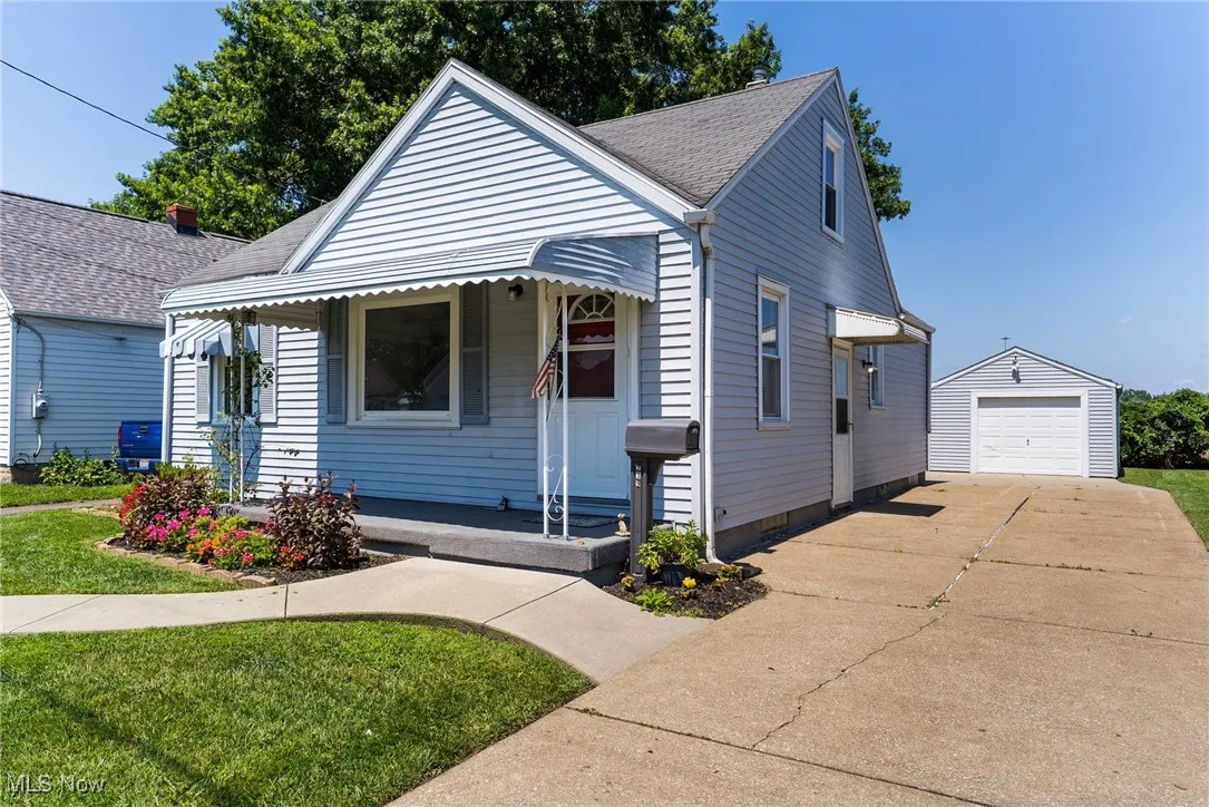 Bungalow-style house featuring a porch, an outdoor structure, driveway, a garage, and a front yard