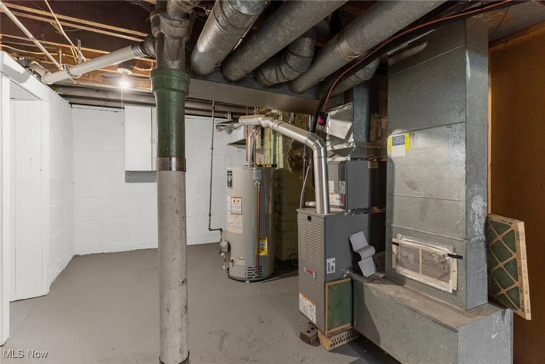Unfinished below grade area featuring gas water heater and heating unit