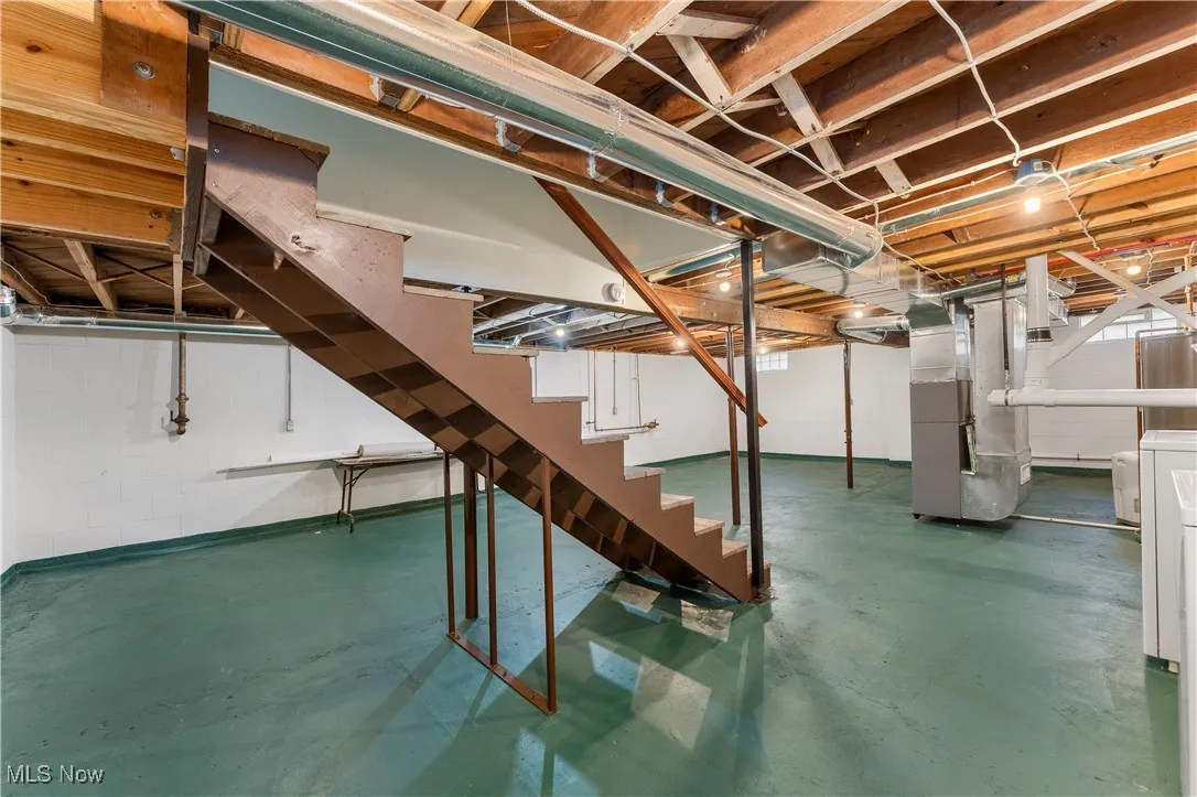Unfinished below grade area with stairs, heating unit, and washer / clothes dryer