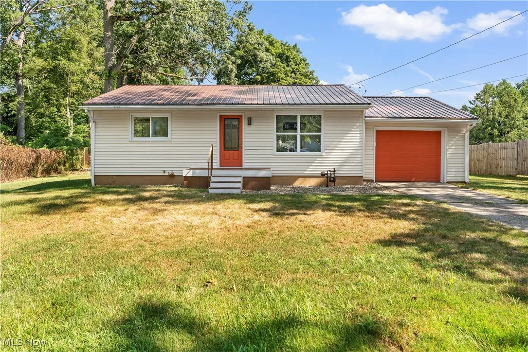 Ranch-style home with a metal roof, concrete driveway, and a garage