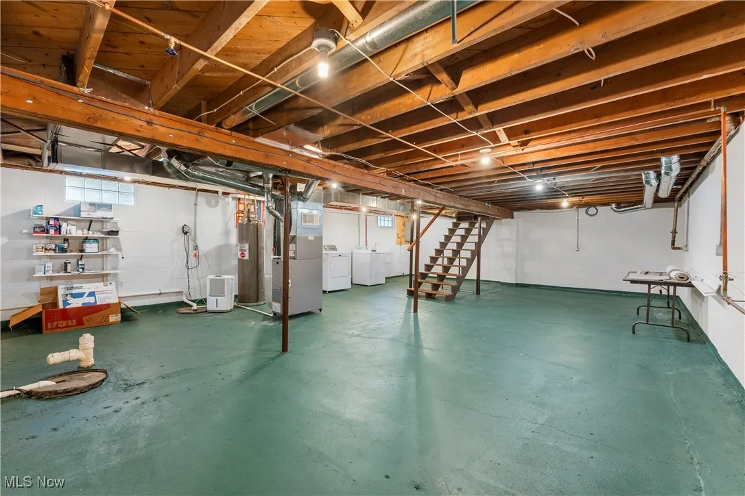 Basement with washing machine and dryer, stairs, heating unit, and electric water heater