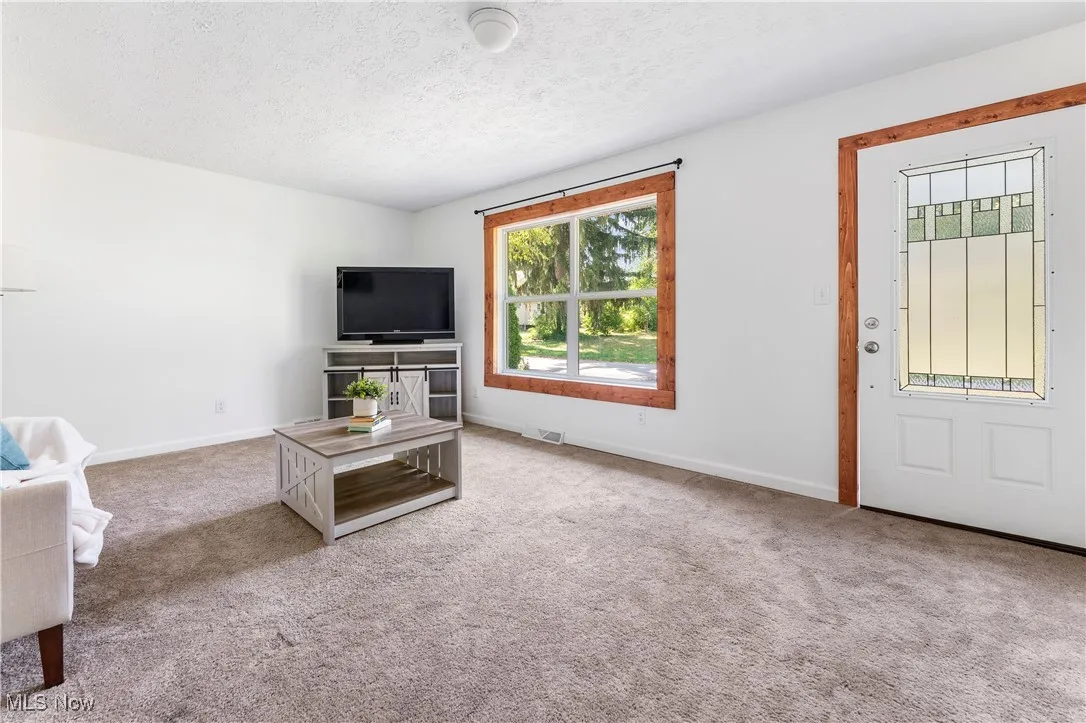 Unfurnished living room featuring carpet floors and a textured ceiling