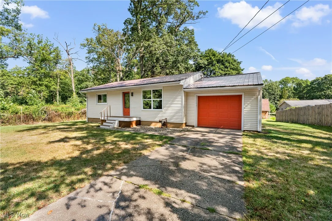 View of front of property with driveway, a garage, and a metal roof