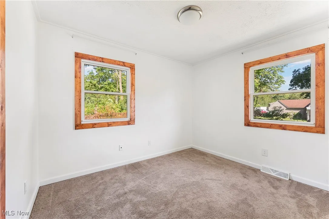 Carpeted spare room with baseboards and ornamental molding