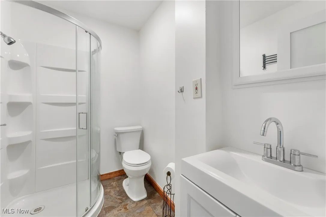 Full bathroom with a shower stall, stone finish flooring, and vanity