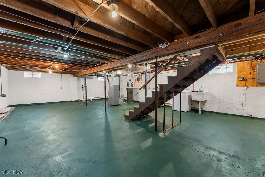 Below grade area featuring washer / dryer, electric panel, heating unit, and stairs