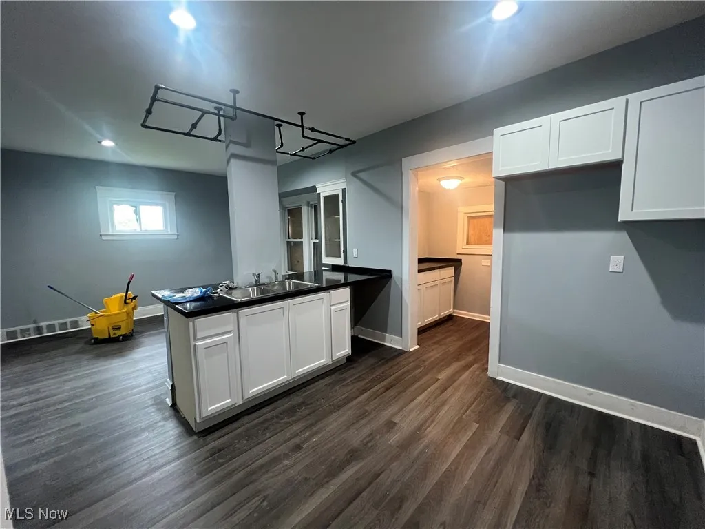 Kitchen featuring a peninsula, dark countertops, recessed lighting, dark wood-style floors, and white cabinetry