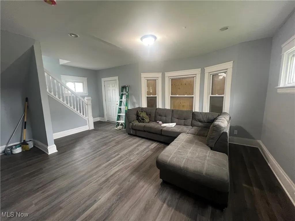 Living room with dark wood-style floors and stairs