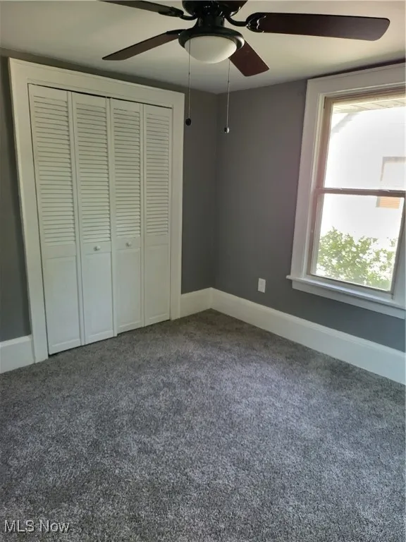 Unfurnished bedroom with carpet flooring, ceiling fan, and a closet