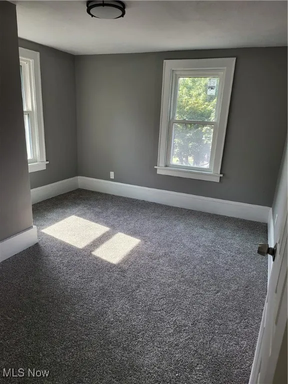 Spare room featuring carpet and baseboards