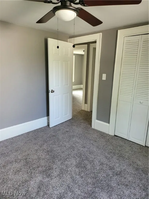 Unfurnished bedroom featuring carpet flooring, a ceiling fan, and a closet