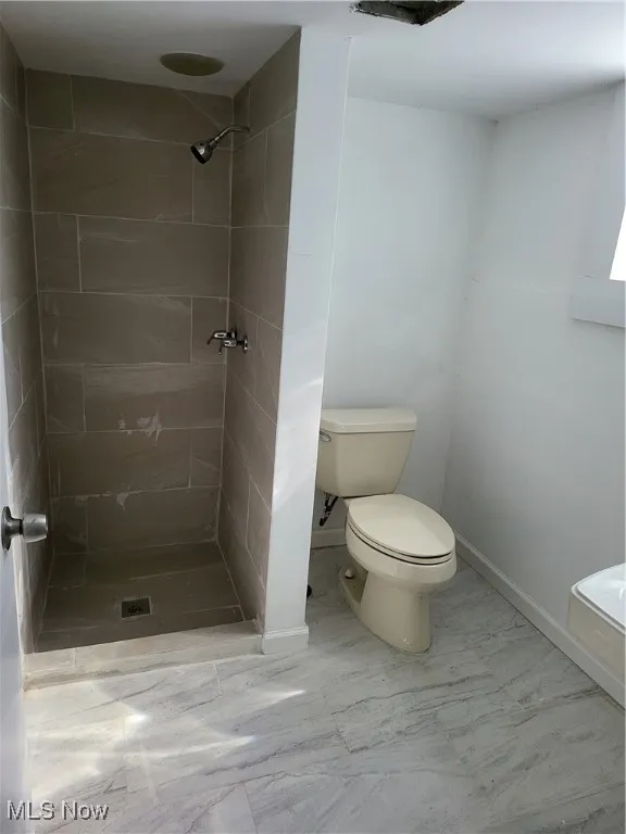 Bathroom featuring a shower stall and marble look tile flooring