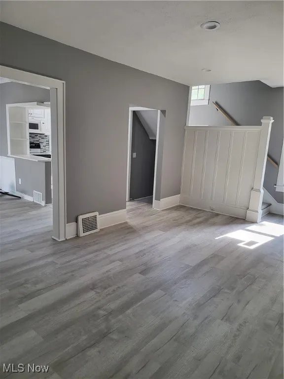 Unfurnished living room with light wood-style flooring and baseboards