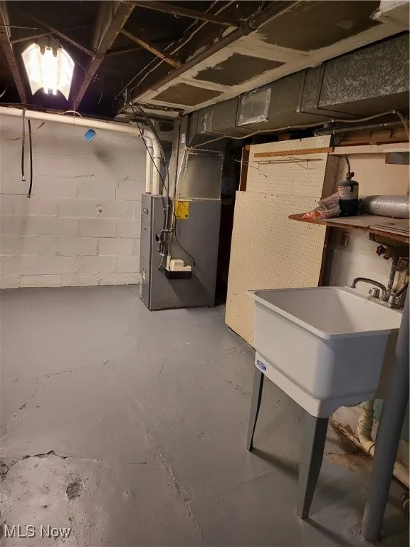 Unfinished basement featuring heating unit and a sink