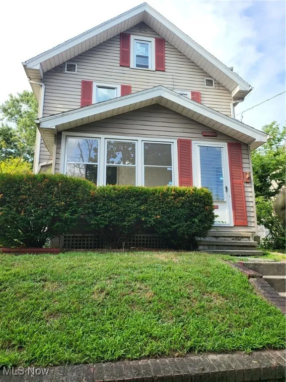 View of front of property with entry steps and a front lawn