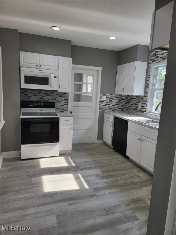 Kitchen with stove, tasteful backsplash, light wood-style flooring, white cabinets, and recessed lighting