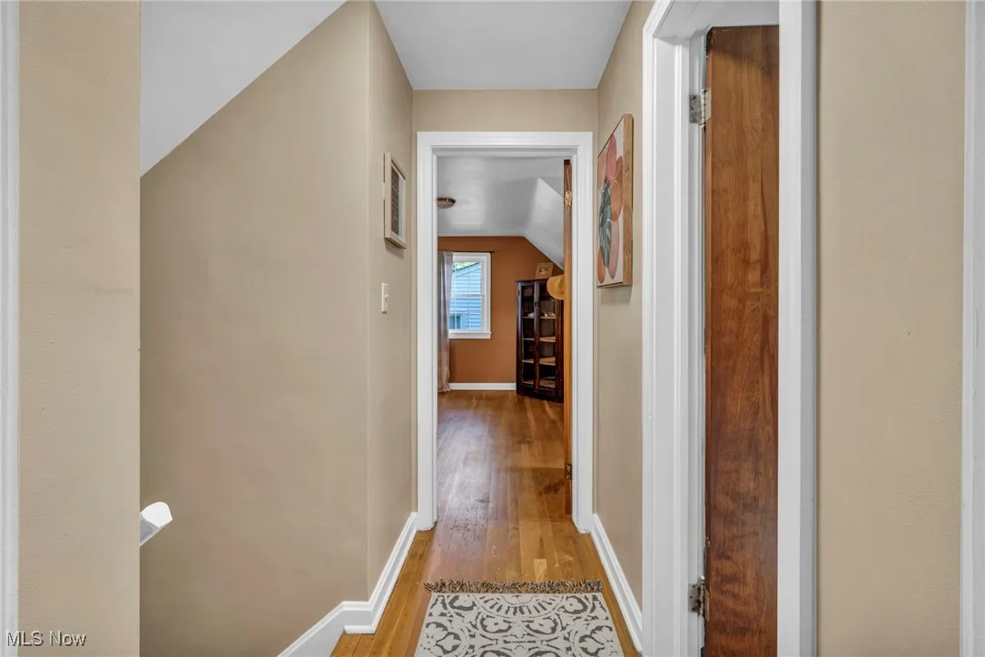 Upstairs hallway featuring original hardwood floors facing office space.