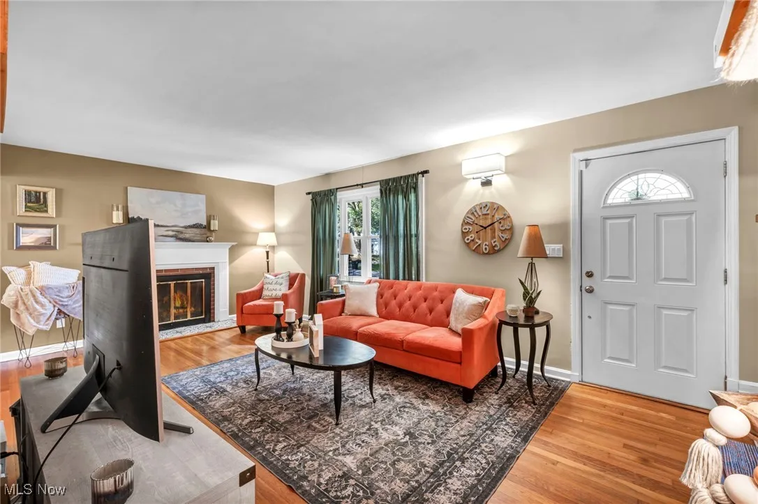 Living room with a brick woodburning fireplace and orginal hardwood flooring.