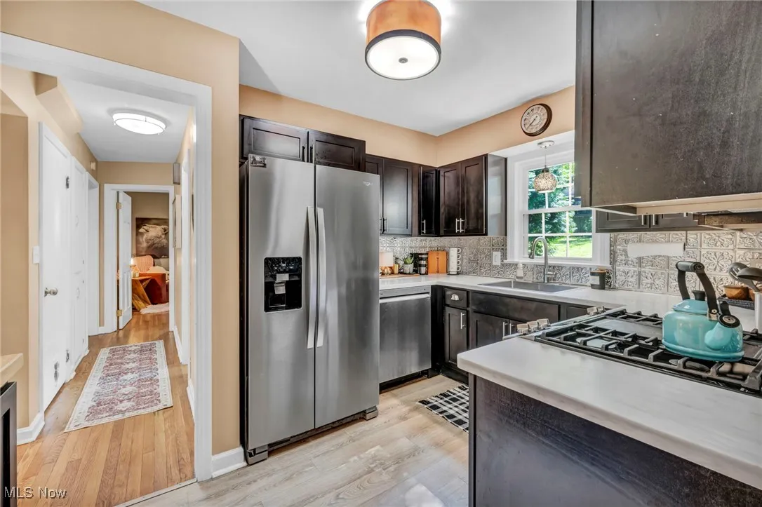 Kitchen with stainless steel appliances facing toward hallway.