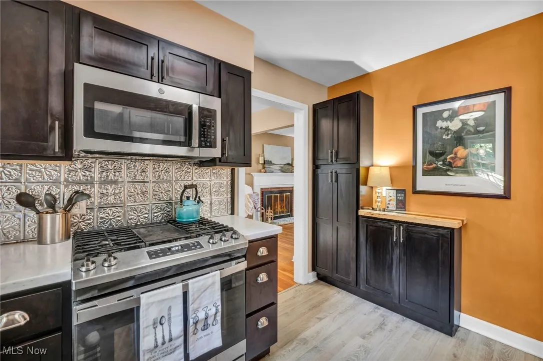 Kitchen featuring stainless steel appliances, tasteful tile backsplash, Corian countertops, LVP flooring, and espresso colored cabinetry.