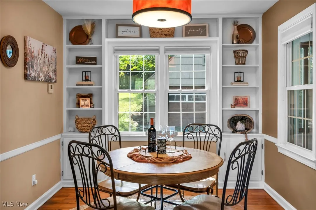 Dining room with built-in shelving and original hardwood floors and view into backyard.