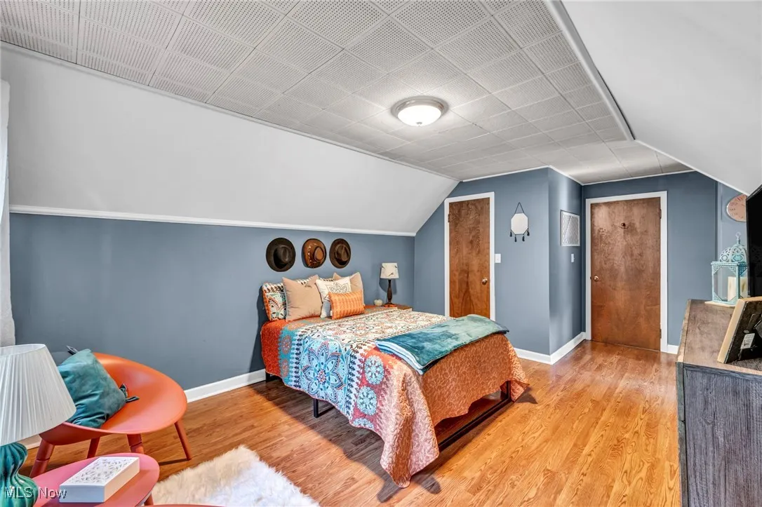 Second floor bedroom with LVP flooring, lofted ceiling facing hallway.
